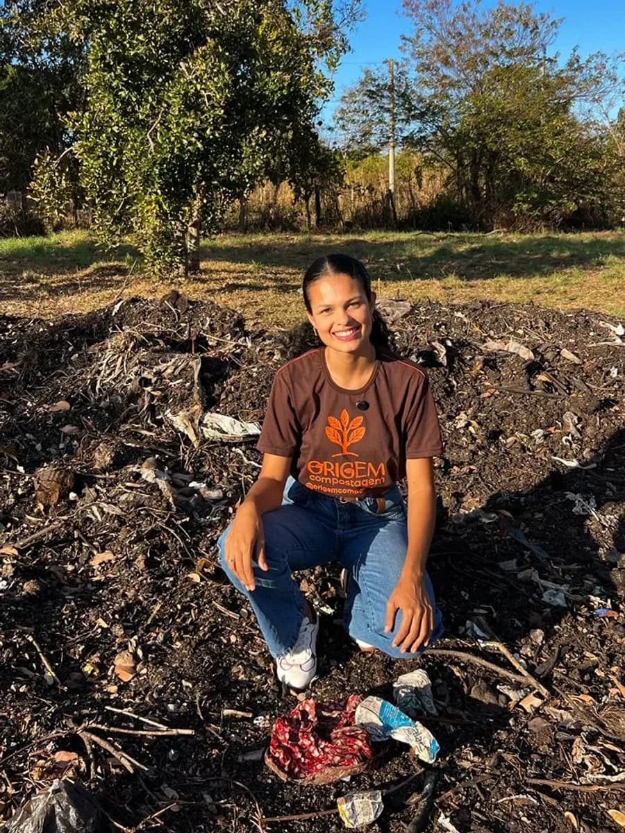 Yasmin Rojas Fonseca, fundadora da Origem Compostagem, sentada no pátio de compostagem.